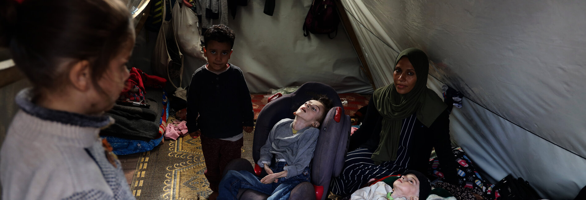 “None of the children has winter clothes. Four of us are sharing a single mattress… The little one sleeps in his carrier... They are all with diarrhea… It’s cold… Hatem has a cough. Their skin is peeling…” Mena, a single mother staying with her four children, including two with disabilities, in a makeshift tent in Al Quds Open University, Gaza. Photo by UNICEF/El Baba, 11 January 2024