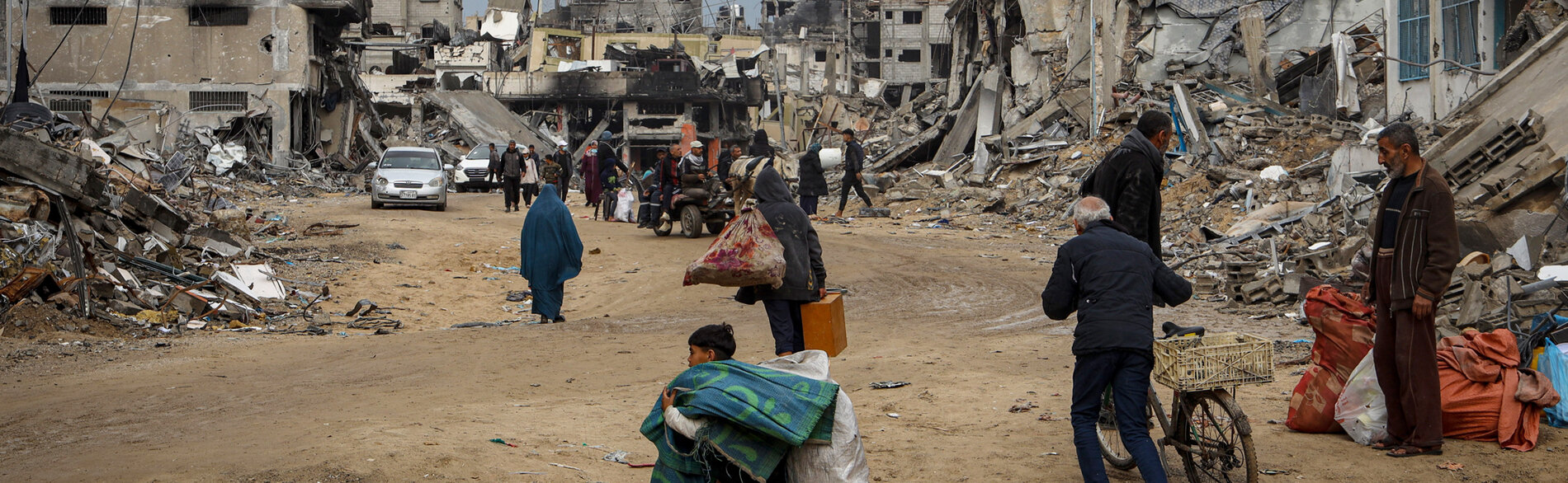 نازحون يحملون مقتنياتهم ويسيرون بين أنقاض المنازل المدمرة في خانيونس جنوب قطاع غزة وهم يبحثون عن ملجأ لهم. تصوير اليونيسف/البابا