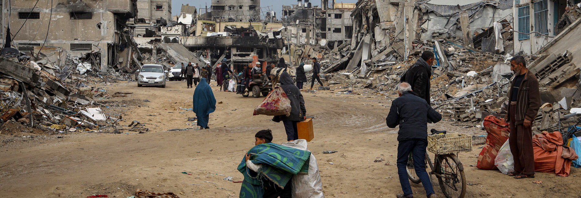 Displaced people carrying their belongings through the rubble of destroyed houses in Khan Younis, in the southern Gaza Strip, as they seek refuge. Photo: UNICEF/El Baba