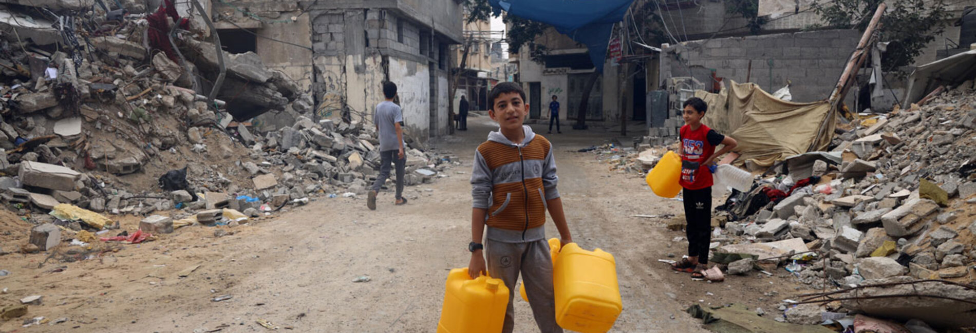 A child carrying empty jerry cans on his way to refill them with drinking water. "I dream of becoming an astronaut," he says. Photo by © UNICEF/El Baba