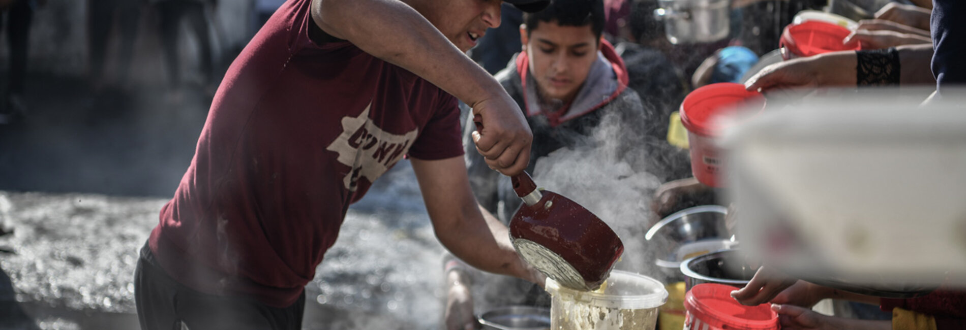 متطوع يوزع الطعام على الناس في رفح، جنوب غزة. ويواجه ما لا يقل عن 576,000 إنسان في غزة – ربع سكانها – مستويات كارثية من انعدام الأمن الغذائي ويتعرّضون لخطر المجاعة. تصوير اليونيسف/عبد زقوت