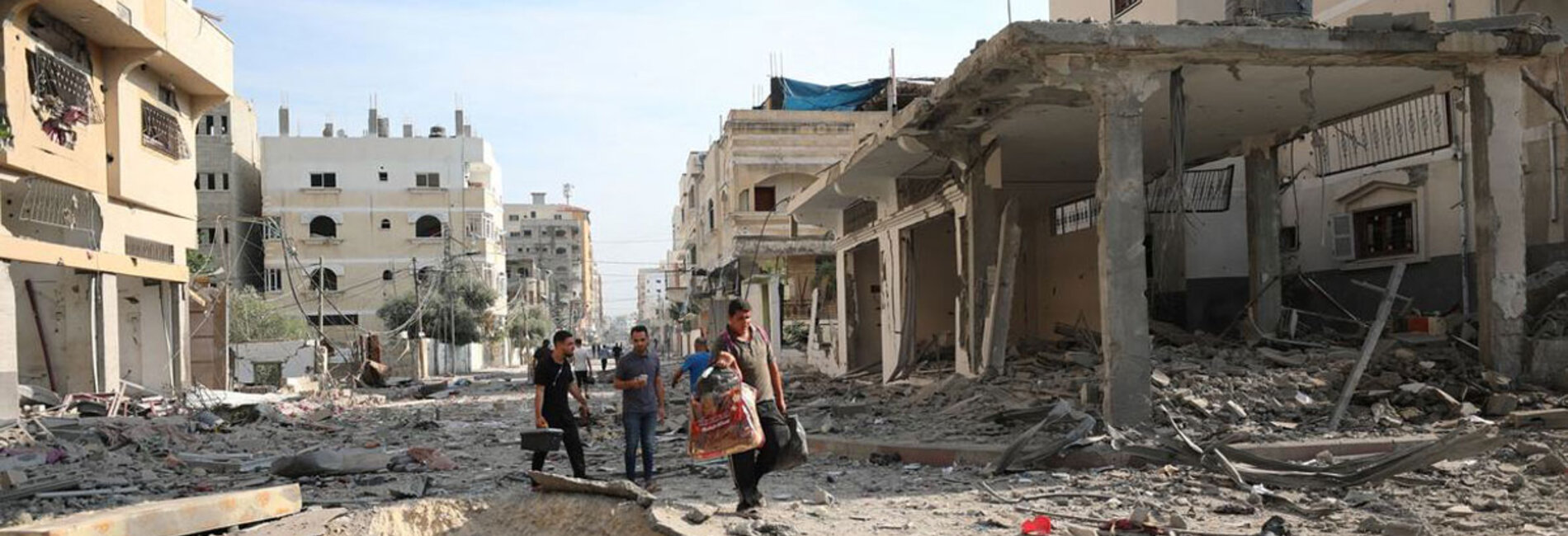 More people are reported killed, injured or missing across the Gaza Strip, with intense fighting continuing around hospitals, as most of the population is displaced and the humanitarian community unable respond to their needs. Picture of men walking through a devastated street in Gaza, by WHO