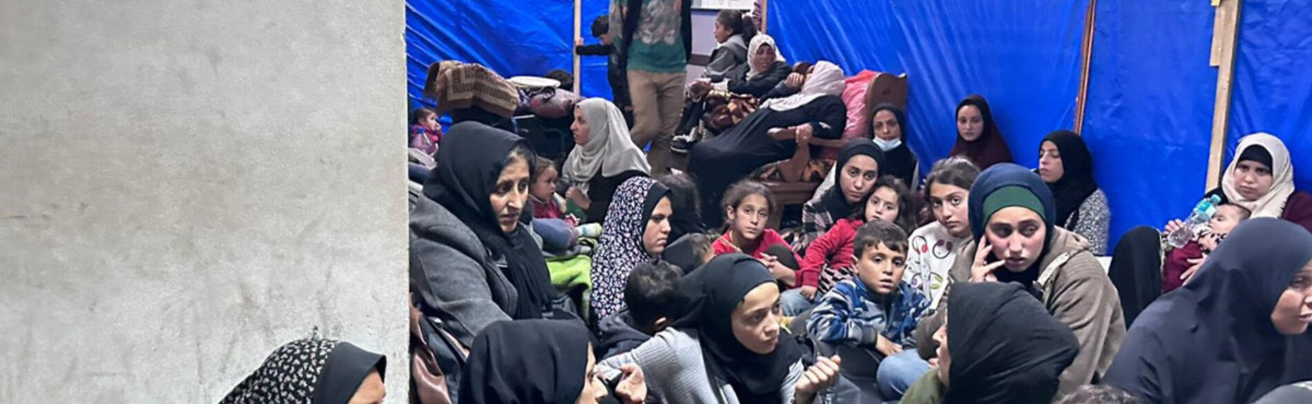 Women and children squeezing into a limited space at an overcrowded UNRWA facility in Khan Younis, amid nearby gunfire and shelling. Photo by UNRWA/Hussein Owda, 23 January 2024 