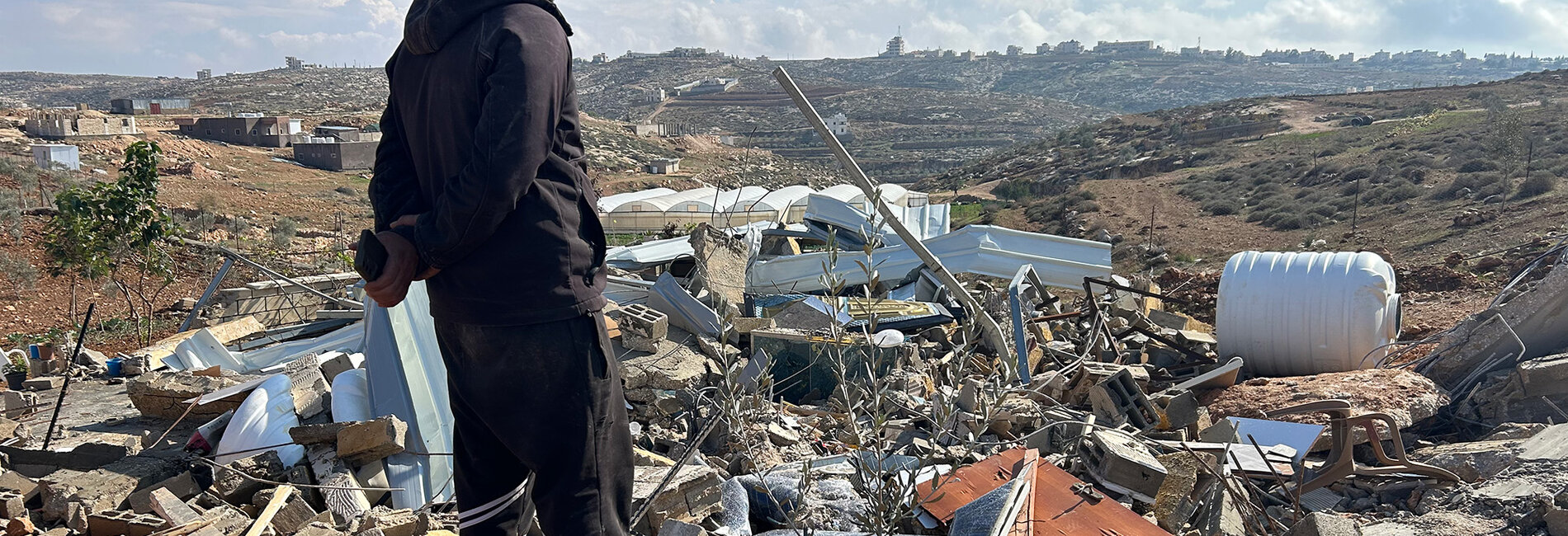 Tha’er Harb looking over what is left of his property after Israeli authorities demolished his home and five other structures in Khallet Al Farra area of As Samu’ for lacking Israeli-issued building permits in Area C of the southern West Bank. Photo by OCHA, 10 December 2025.