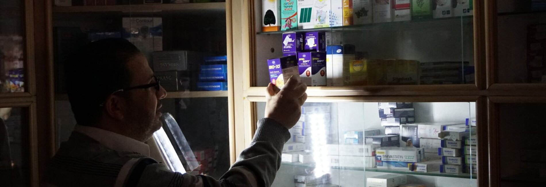 Pharmacist using emergency light, Gaza 27 April 2017. © Photo by OCHA.