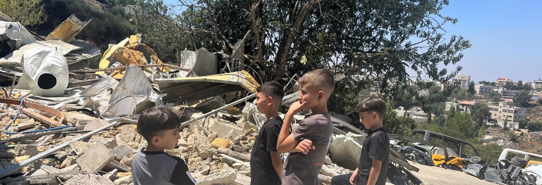 Children standing next to a demolished car-painting workshop in Dura Al Qar’a, Ramallah governorate. Destroyed for lacking an Israeli building permit, the structure was the source of livelihood for a family of nine. Photo: OCHA