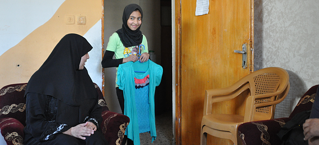 אפנאן (בת 11) מראה את הבגדים החדשים שקנתה לה משפחתה בסיוע תוכנית שוברים © תוכנית המזון העולמית / קולין קמפשר