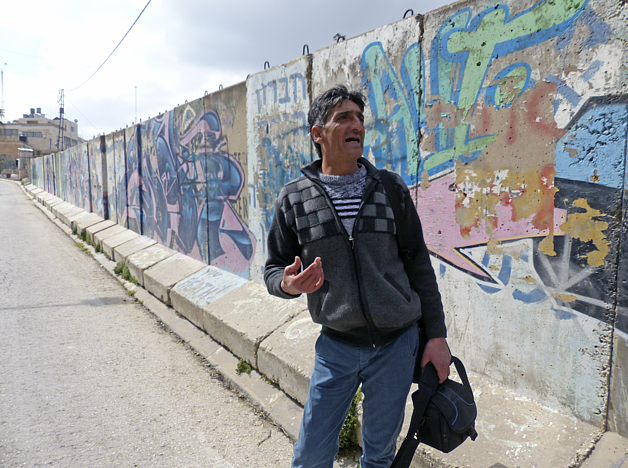 Abu Shamsiyyi standing by the wall outside his house in Tel Rumeida, Hebron, March 2017. Al Shuhada Street, Hebron city, March 2017. ©  Photo by OCHA.