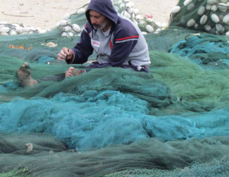 Gaza fisherman working on his nets Gaza fishing wharf. Gaza city, April 2013. Photo by OCHA