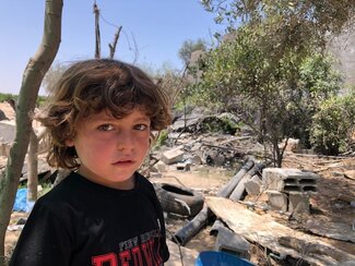 A child in Gaza beside a destroyed structure from the May escalation, 9 June 2021. Photo by OCHA