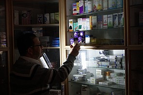 Pharmacist using emergency light, Gaza 27 April 2017. © Photo by OCHA. Pharmacist using emergency light, Gaza 27 April 2017. © Photo by OCHA.