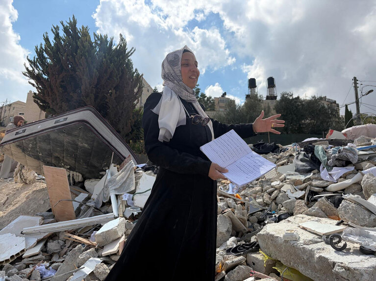 Hanin holds her daughter’s school notebook, retrieved from beneath the rubble of their home after it was demolished by Israeli authorities in At Tur, East Jerusalem. Residents said they were prevented from retrieving their belongings before the demolition. Photo by OCHA