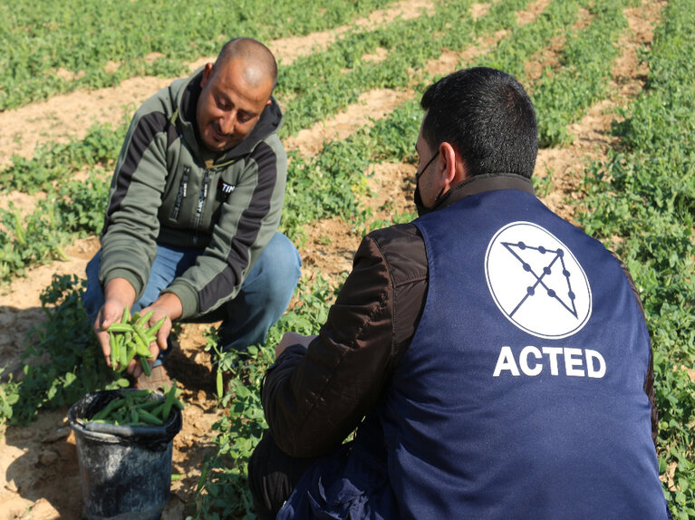 Omar on his field with a staff member from ACTED.