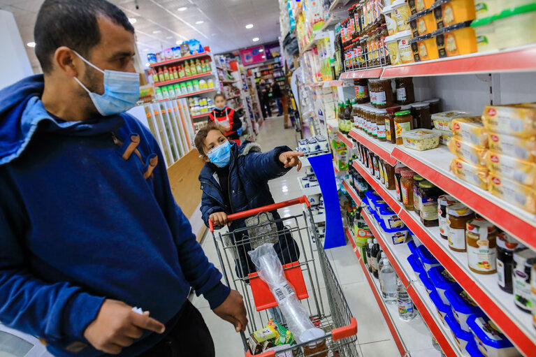Jaber and his daughter select the groceries they need most, for which they would pay with an CRS electronic voucher. Photo by Mohamed Reefi for CRS