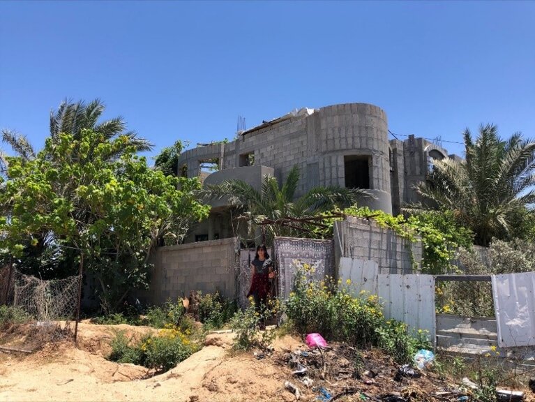 Lialy, one of the daughters, in front of her Awaja home in Beit Lahiya, 7 July 2021. Photo by OCHA.