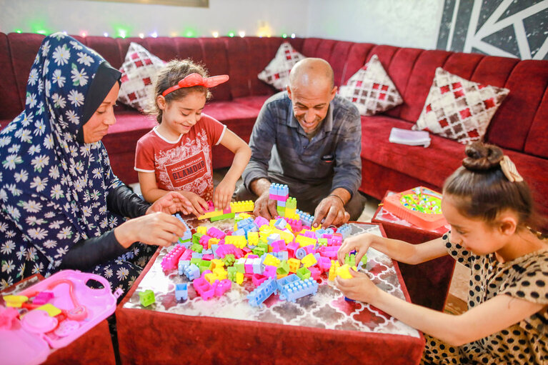 Asma and Sade playing with two of their daughters in their renovated livingroom.