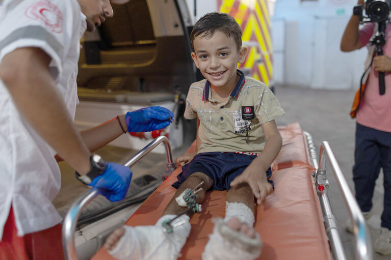 An aid worker supporting the medical evacuation of an injured child in the Gaza Strip. Photo by WHO