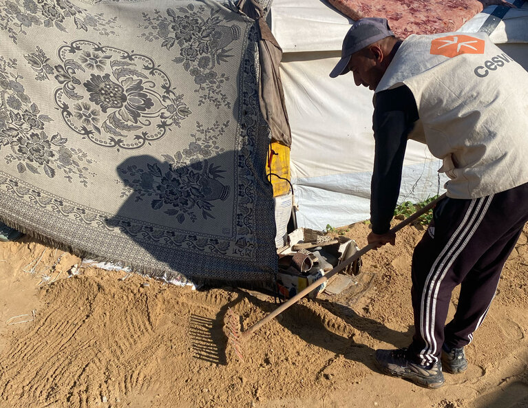 Aid worker leveling sand in a makeshift collective shelter in Gaza, to strengthen flood resilience and improve access to essential services ahead of the rainy season. Photo by CESVI