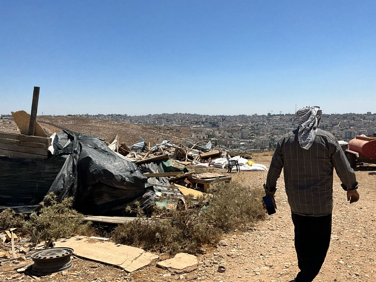 A Palestinian Bedouin man walks among the remains of his family’s structures in North Beit Hanina Bedouin community in Jerusalem, after the Israeli authorities demolished them and displaced 23 people on 27 July 2026. Photo by OCHA 