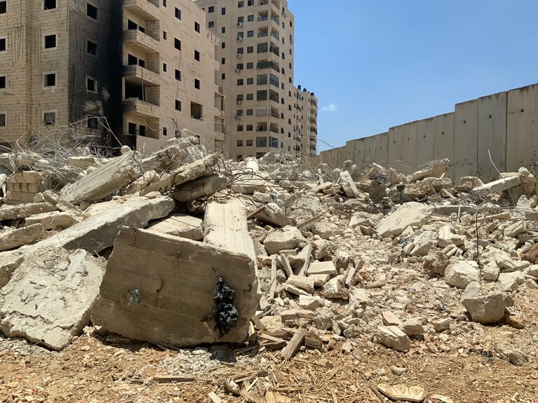 What remains of a Palestinian-owned multi-storey building demolished by Israeli authorities in Kafr Aqab on 22 June 2026, displacing two households. The Barrier is seen on the right. Photo by OCHA