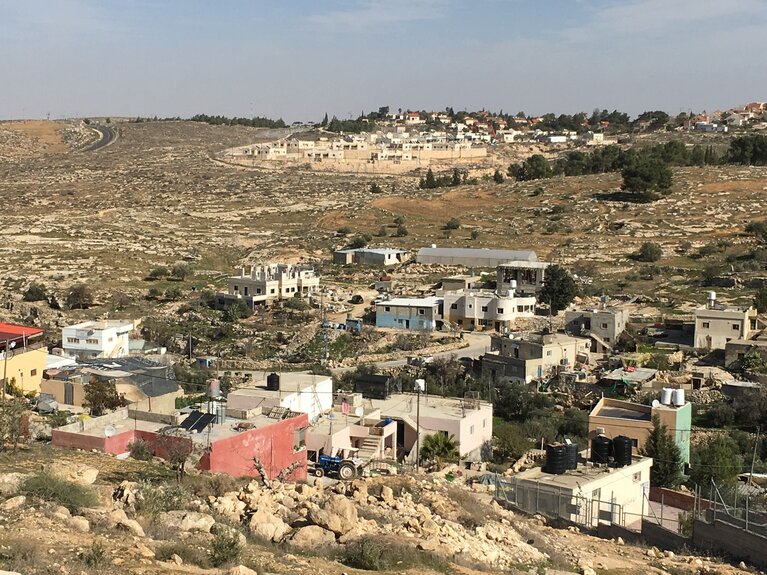 The Palestinian village of At Tuwani against the backdrop of the Israeli settlement of Ma’on. Photo by Tanya Habjouqa for OCHA, 2021.