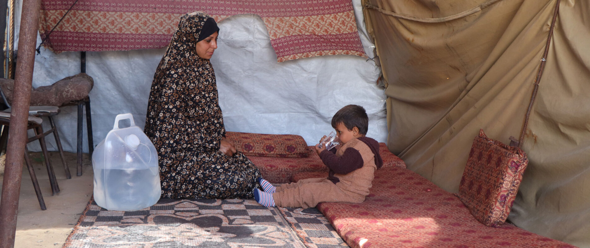 Suad* giving clean water to her three-year-old son Rasheed*