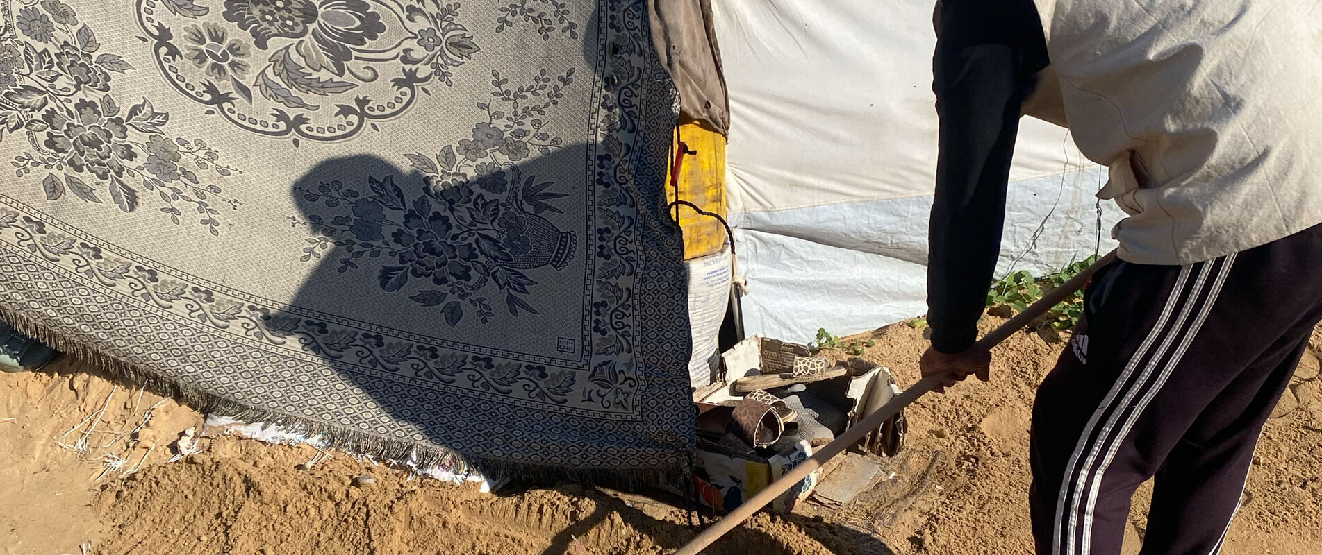 Aid worker leveling sand in a makeshift collective shelter in Gaza, to strengthen flood resilience and improve access to essential services ahead of the rainy season. Photo by CESVI