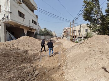 Palestinians make their way through the remains of a bulldozed road in Jenin city following an operation carried out by Israeli forces on 11 March 2025. Photo by Jenin municipality.    