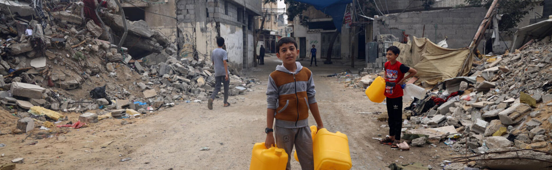 A child carrying empty jerry cans on his way to refill them with drinking water. "I dream of becoming an astronaut," he says. Photo by © UNICEF/El Baba