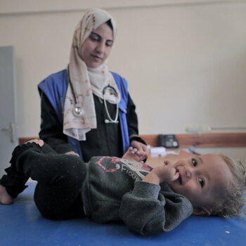 May 26, 2024, Rafah: A staff member from the UNRWA Health Team at the Tel Al-Sultan Health Center in Rafah area conducts a medical examination for a displaced child.© 2024 UNRWA Photo by Mohammed Hinnawi May 26, 2024, Rafah: A staff member from the UNRWA Health Team at the Tel Al-Sultan Health Center in Rafah area conducts a medical examination for a displaced child.© 2024 UNRWA Photo by Mohammed Hinnawi